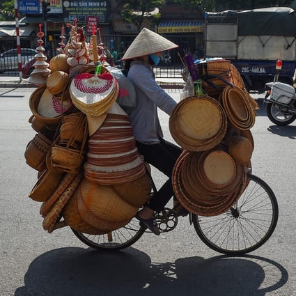 Motorists and a street vendor ride down a street in Hanoi. Photo: AFP