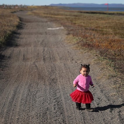A one-year-old girl walks along a road in the Alaskan village of Kivalina, which is being swallowed by rising oceans, on September 13, 2019. Photo: Getty Images/AFP