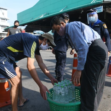 Staff members deliver drinking water to people living in the lockdown area near a seafood market in Samut Sakhon, Thailand on Saturday. Photo: Xinhua
