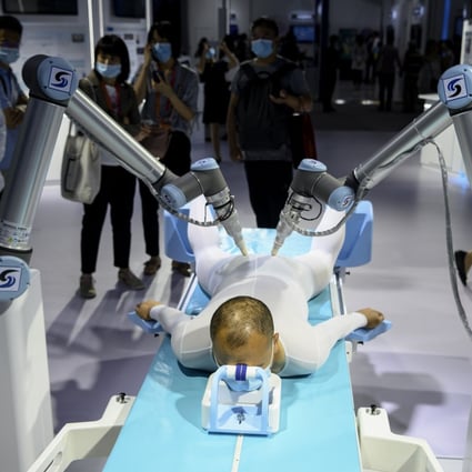 A man tries out a Chinese traditional medicine treatment using robotic arms at the China International Fair for Trade in Services in Beijing on September 6. AI-driven automation will transform almost every service job in some way, but they will replace very few because there’s always something that “globotics” can’t do. Photo: AFP