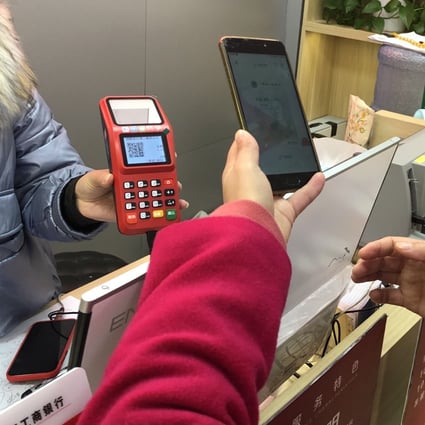 Li Lan, who won a 200-yuan red packet in Suzhou’s e-yuan test, scans a QR code with her smartphone to make a payment at an electronics shop. Photo: Orange Wang