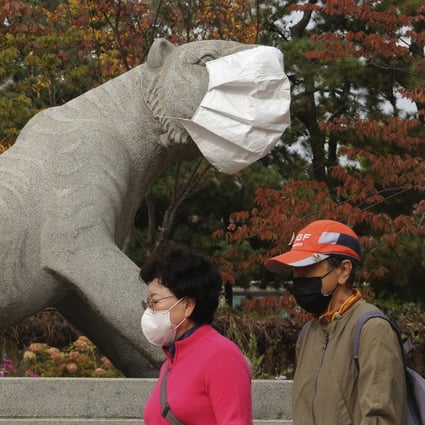 Passers-by and a statue sport face masks in a Seoul park. Photo: AP