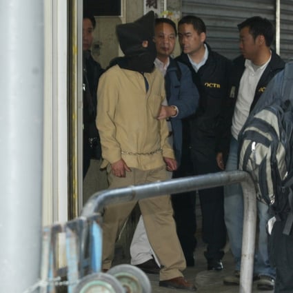 Police escort a hooded suspect, thought to be Kwai Ping-hung, out of a building in Yau Ma Tei on December 24, 2003. Photo: SCMP