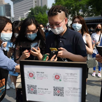 People in Beijing using a phone app to scan a code proving their health and travel status before entering a shopping mall. Photo: AFP