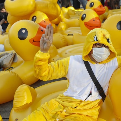A protester flashes the three-finger protest gesture while reclining on an inflatable yellow duck, which has become a good-humoured symbol of resistance during the pro-democracy rallies in Thailand. Photo: AP