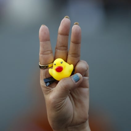 The three-finger protest gesture is flashed by a demonstrator holding a yellow duck, which has become a good-humoured symbol of resistance during anti-government rallies in Thailand. Photo: AP