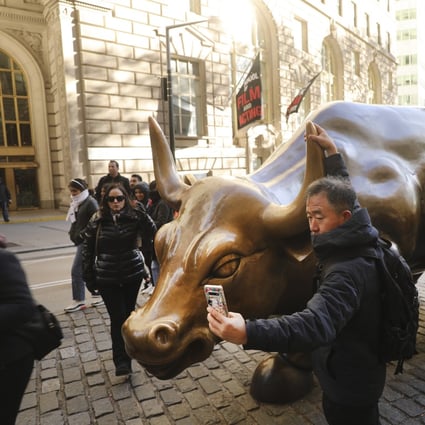 A Chinese tourist taking photos in front of the "Charging Bull" sculpture in lower Manhattan in New York City. Global stocks rallied from New York to Seoul and Shanghai in 2020 as investors turned a crisis year into outsized gains. Photo: AFP