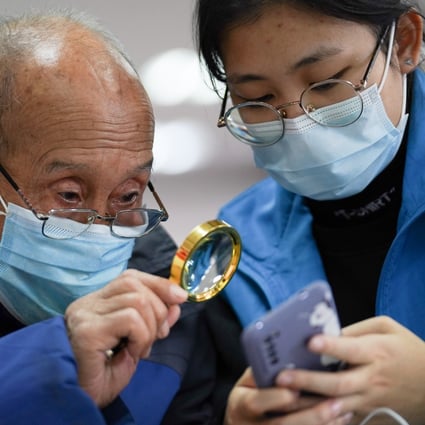 A student volunteer shows a senior resident how to make a hospital appointment using mobile phone at a community activity centre in Beijing on December 8, 2020. Photo: Xinhua
