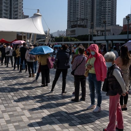 People wearing protective masks maintain social distancing while standing in line at a community testing centre in Hong Kong on December 5. Only 8 per cent of Hongkongers aged under 30 polled recently said they would “definitely” get the free Covid-19 vaccines provided by the government. Photo: Bloomberg