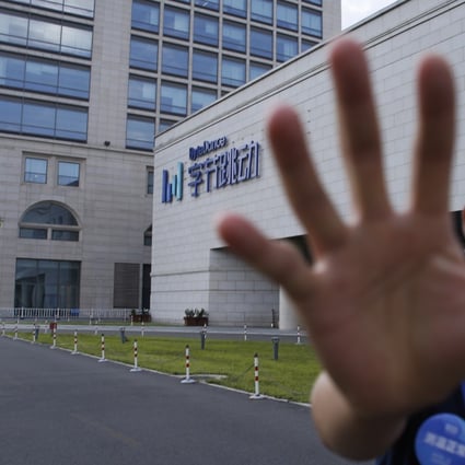 A security guard attempts to stop a photographer in front of the ByteDance headquarters building in Beijing, China, 03 August 2020. Photo: EPA-EFE
