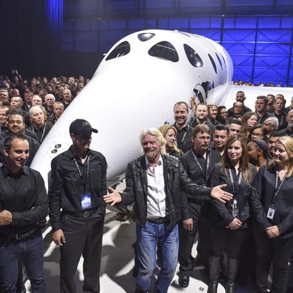 Virgin Galactic's Richard Branson (front, centre) gathers with Virgin Galactic employees in front of the SpaceShip Two VSS Unity after a roll-out ceremony. The company is set to begin commercial space flights this year. Photo: Getty Images