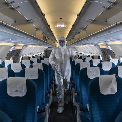 A worker wearing a protective suit disinfects a Vietnam Airlines at Noi Bai International Airport in Hanoi. Photo: AFP