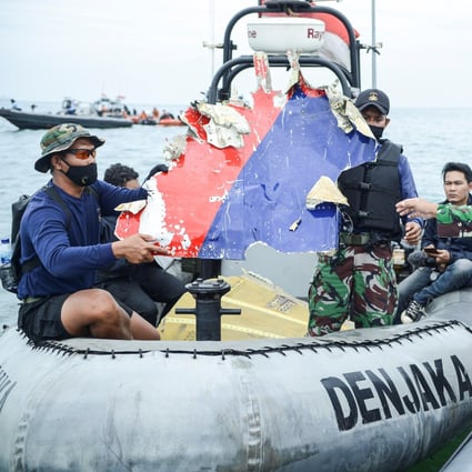 Indonesian Navy personnel transport debris believed to be from the Sriwijaya Air SJ-182 jet. Photo: Antara Foto via Reuters