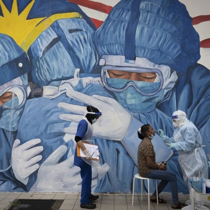 A doctor collects a sample for testing from a lady at a coronavirus screening in Shah Alam, Malaysia. Photo: AP