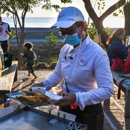 A waitress with a face mask serves customers at a restaurant in Bangpu, Thailand. Photo: AFP