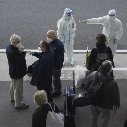 A worker in protective gear directs members of the World Health Organization team on their arrival at the airport in Wuhan on Thursday. Photo: AP