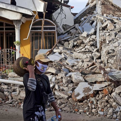 A man walks past a house that collapsed in Friday's earthquake in Mamuju, West Sulawesi. Photo: AP