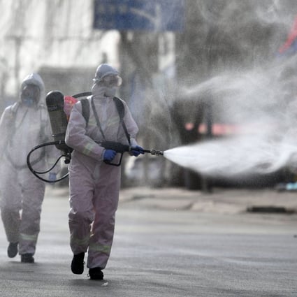 Workers spray disinfectant on a street in Shijiazhuang’s Gaocheng district. Photo: STR/CNS/AFP