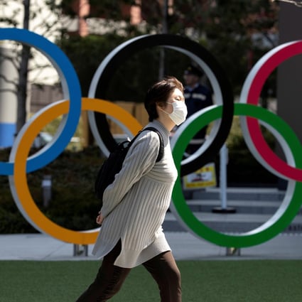 A woman walks past the Olympic rings in front of the Japan Olympics Museum, in Tokyo, in March 2020. Photo: Reuters