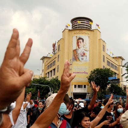 Pro-democracy demonstrators give a three-finger salute while marching against the backdrop of a portrait of King Maha Vajiralongkorn in Bangkok. Photo: Reuters