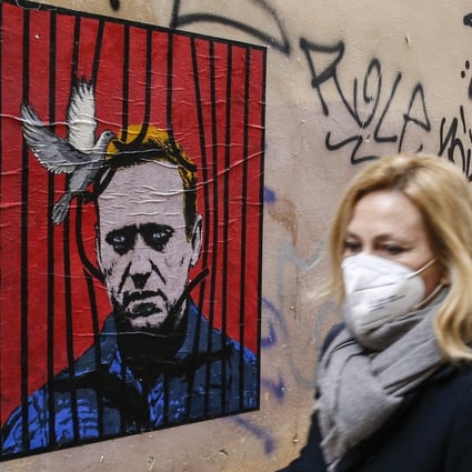 A woman in Rome walks by a poster depicting Alexei Navalny behind bars with a dove freeing him from detention. Photo: EPA-EFE