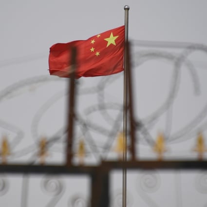 The Chinese flag behind razor wire at a housing compound in Yangisar, south of Kashgar, in China’s western Xinjiang region. Photo: AFP
