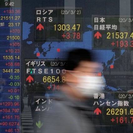 A pedestrian walks past an electric quotation board displaying share prices of the Tokyo Stock Exchange. in Hong Kong, investors suffer a bruising week as the Hang Seng Index retreats by almost 4 per cent. Photo: AFP