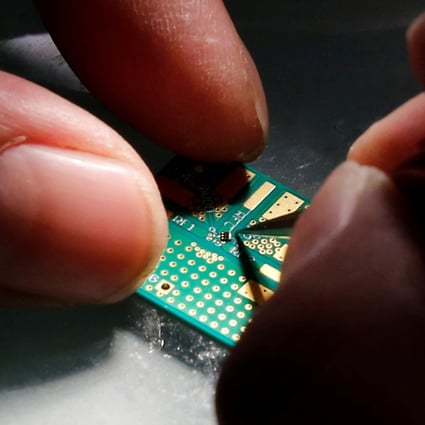 A researcher plants a semiconductor chip on a circuit board at Tsinghua Unigroup research centre in Beijing. Photo: Reuters
