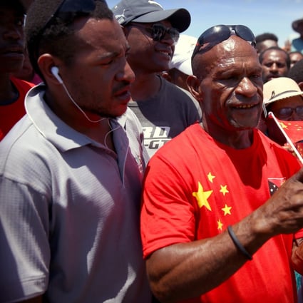 A Papua New Guinean man wearing a shirt with the Chinese and Papua New Guinea flags takes a photo on his mobile phone during the 2018 opening of Independence Boulevard in Port Moresby. Photo: Reuters