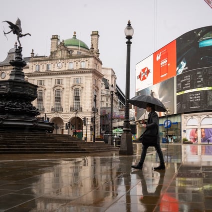 A man with an umbrella walks through Piccadilly Circus in London. Photo: DPA