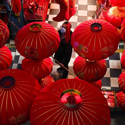 A vendor of Lunar New Year decorations looks up near giant lanterns hung outside a store ahead of the Year of the Ox Chinese Lunar New Year celebrations in Wuhan in central China's Hubei province. Photo: AP Photo