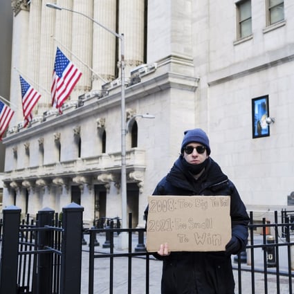 An activist, standing in front of the New York Stock Exchange on January 28, holds a sign calling for an increase in the capital gains tax. Photo: EPA-EFE