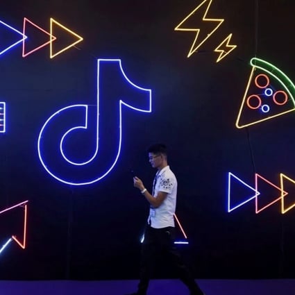 A man holding a phone walks past a logo for ByteDance's app TikTok, known locally as Douyin, at the International Artificial Products Expo in Hangzhou. Photo: Reuters