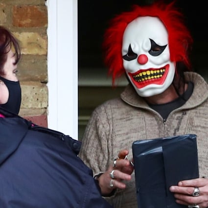 Volunteers hand out a Covid-19 home test kit to a resident wearing a clown mask in Woking, Britain on Tuesday. Photo: Reuters