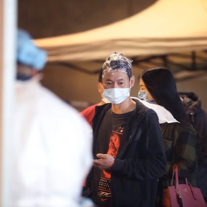 A man halfway through getting his hair dyed lines up for testing in Sham Shui Po during a lockdown on Tuesday. Photo: Handout