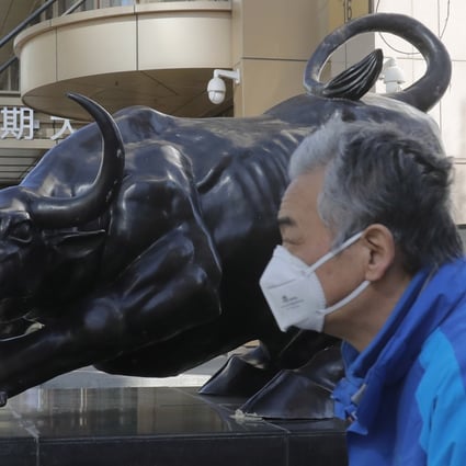 A man wearing walks by a bull sculpture in Beijing in March last year. In Hong Kong, tech stocks faltered on February 4 to end a three-day advance in the Hang Seng Index. Photo: EPA-EFE