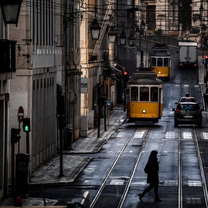 A woman crosses a street past trams in Lisbon. Photo: AFP