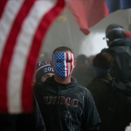 A demonstrator wears an American flag mask during a protest at the US Capitol in Washington on January 6. The obsessive conviction of Donald Trump and his followers about US election fraud took contrarianism to excessive extremes. Photo: Bloomberg