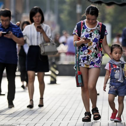 Pedestrians view their smartphones as they walk along a pavement in Beijing. China’s newly implemented antitrust guidelines aim to keep in check monopolistic practices of China’s Big Tech companies. Photo: AP