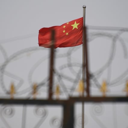 The Chinese flag flies behind razor wire at a housing compound in Xinjiang on June 4, 2020. The EU, in deciding whether to approve the investment deal, should think long and hard about China’s track record including in violating human rights. Photo: AFP