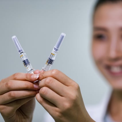 A Sinovac staff member displays two doses of its Covid-19 vaccine. Photo: Xinhua