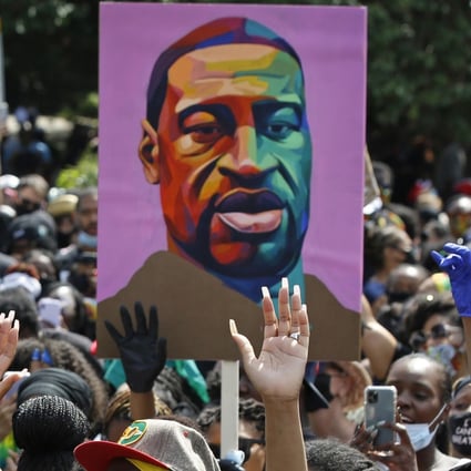 Protesters hold up an image of George Floyd at a Black Lives Matter rally in New York in June. Photo: AP