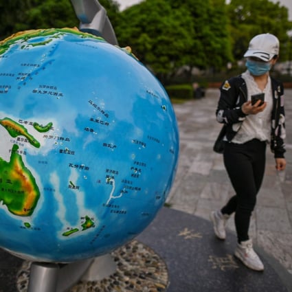 A woman wearing a face mask looks at a globe in a park in the Chinese city of Wuhan in April 2020. Photo: AFP