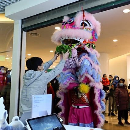 A man makes an offering as a lion dance team perform inside a mall in Beijing on Tuesday, on the fifth day of the Lunar New Year. Photo: AFP