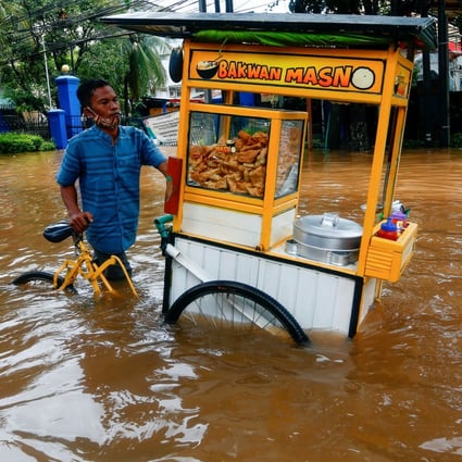A street vendor pushes his cart through the water in an area affected by floods following heavy rains in Jakarta, Indonesia on Saturday. Photo: Reuters
