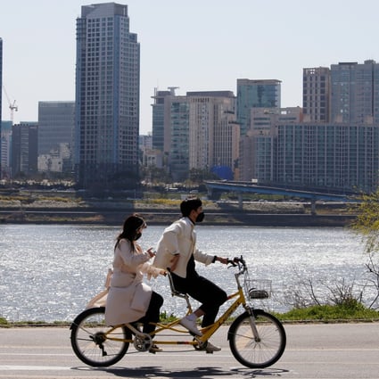 A couple wearing masks to protect against the coronavirus ride next to the Han River in Seoul, South Korea on April 4, 2020. The relative resilience and maturity of South Korea’s economy is the key factor underpinning confidence in the commercial property sector. Photo: Reuters