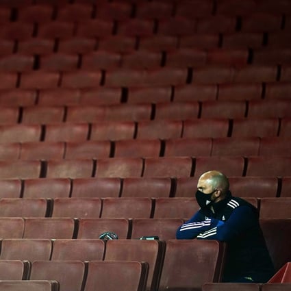 A stadium staff member wearing a protective face mask sits in the stands during an English Premier League match between Arsenal and West Ham United in London in September 2020. Photo: EPA
