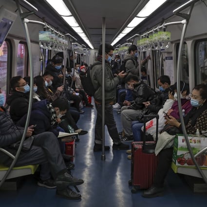 Commuters wearing face masks to help curb the spread of the coronavirus ride on a subway train in Beijing in February 2021. The Global Prediction System predicts new Covid-19 cases will hit a seasonal low in April at about 9.2 million worldwide but then climb to about 14 million cases in July. Photo: AP Photo