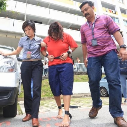 Gaiyathiri Murugayan (centre), is escorted from her Bishan flat in 2016 after the death of her 24-year-old Myanmar domestic helper Piang Ngaih Don. Photo: Today Online