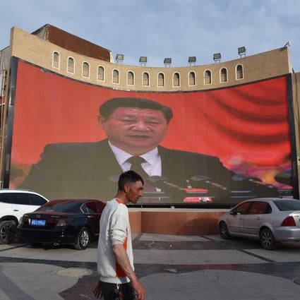 A man walks past a screen showing images of China’s President Xi Jinping in Kashgar, in China’s Xinjiang Uygur autonomous region. Photo: AFP